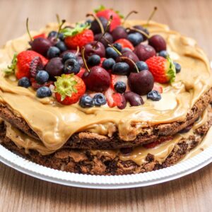 Delicious layered chocolate cake with fresh berries and peanut butter cream on a plate.